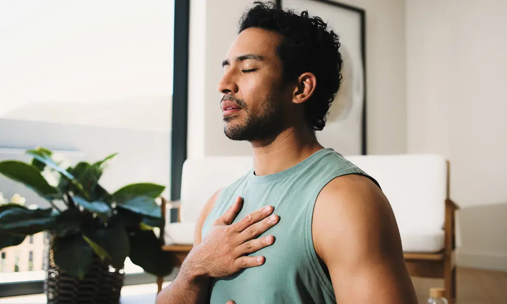 A man practices deep breathing with a hand on his chest