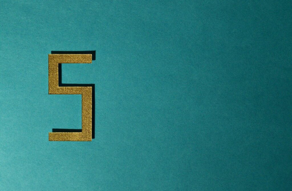 Teal background with a gold glitter number 5 cut out displayed on the left side of the image