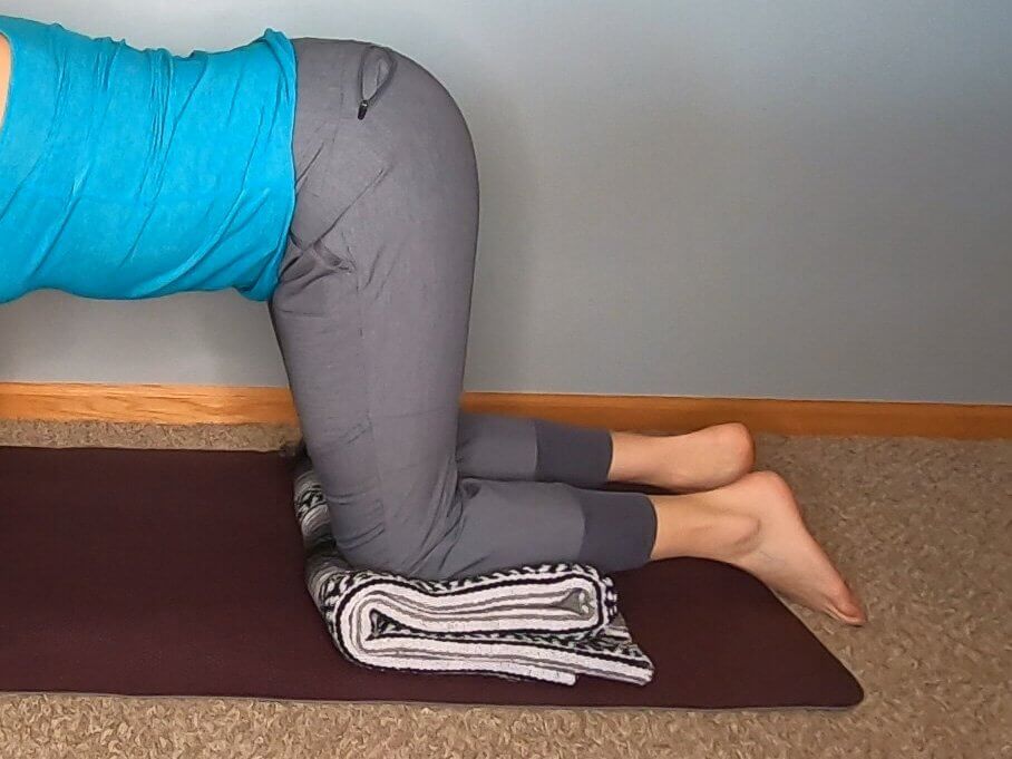 On hands and knees with a blanket folded over to stack to raise height and reduce flexion of ankles