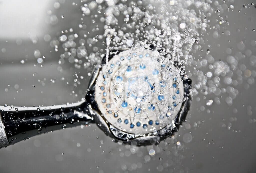 Close up image of waterfall shower head with water coming out towards camera lens of image
