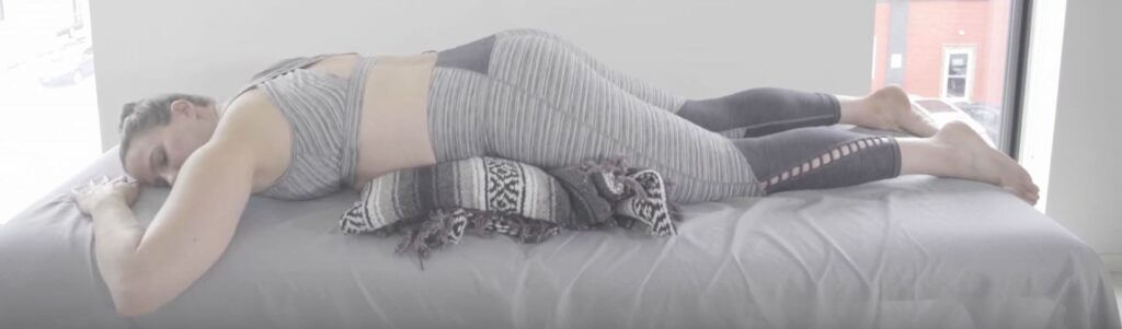 Laura laying face down on surface with a stack of blankets folded and resting underneath her hips