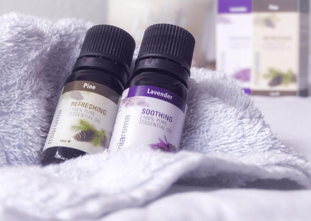 2 bottles of miaroma pine and lavender scent bottles in towel which both say 100% pure essential oil