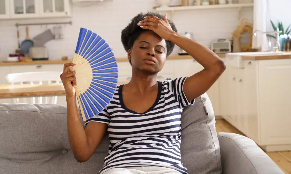 menopause-hot-flash A woman sits on a couch and fans herself