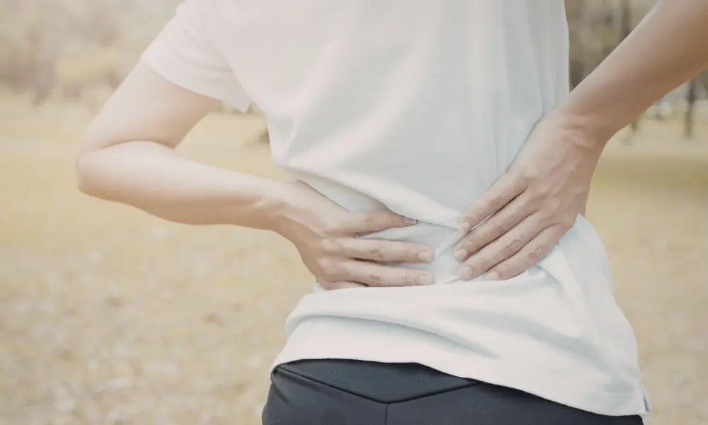 person standing and holding the sides of their lower waist in discomfort