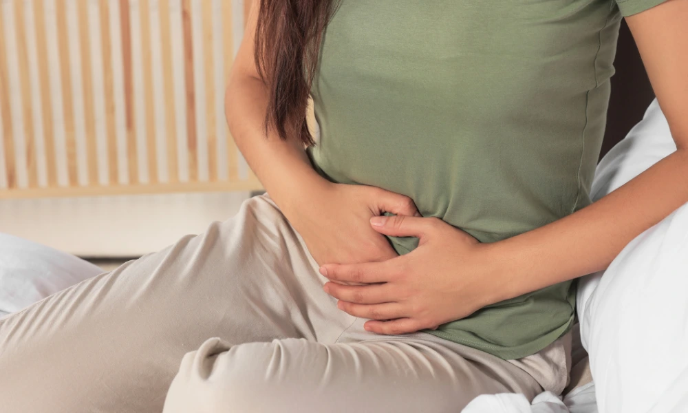 Close up of a person sitting and holding their lower pelvic area