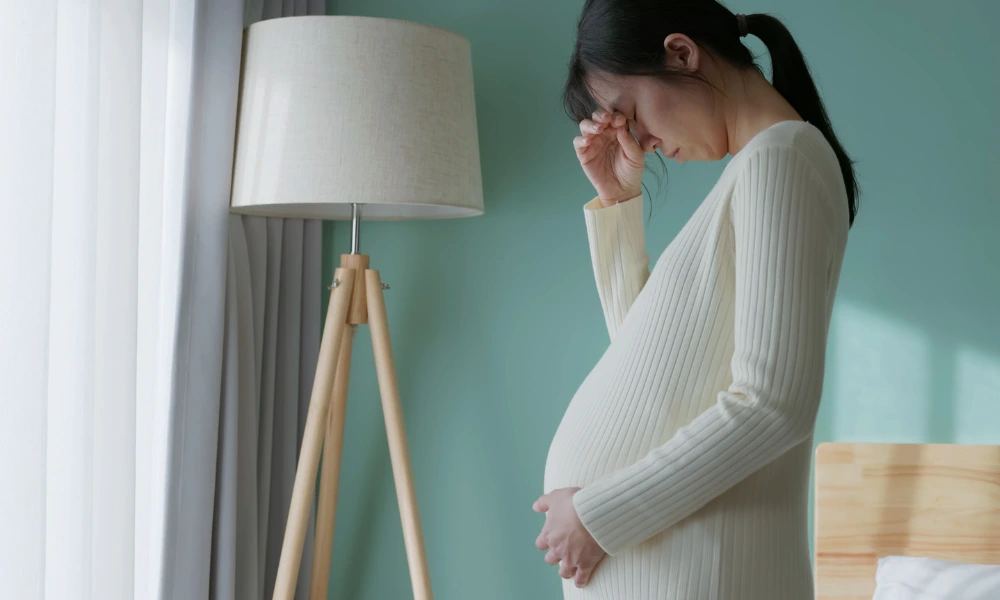 Pregnant person holding her hand up to her face in sadness or frustration