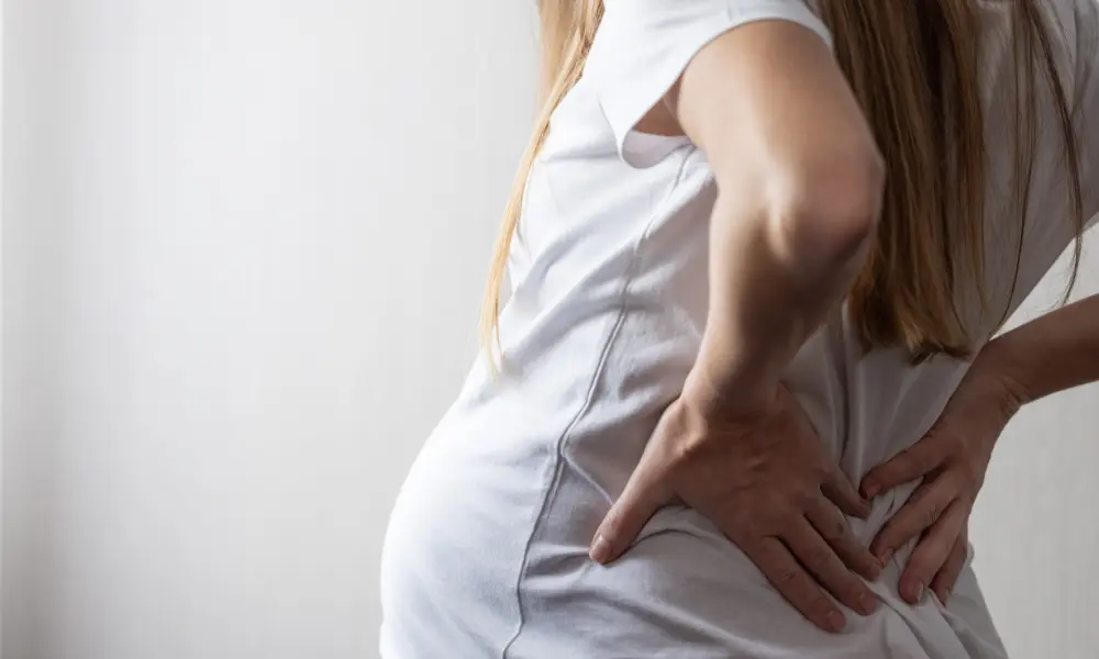 SI-joint-pain-pregnancy Pregnant person holding their lower back in discomfort