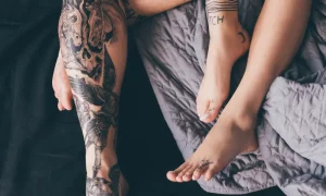 a zoomed in look at two people's lower legs laying on a bed