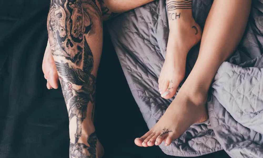 a zoomed in look at two people's lower legs laying on a bed