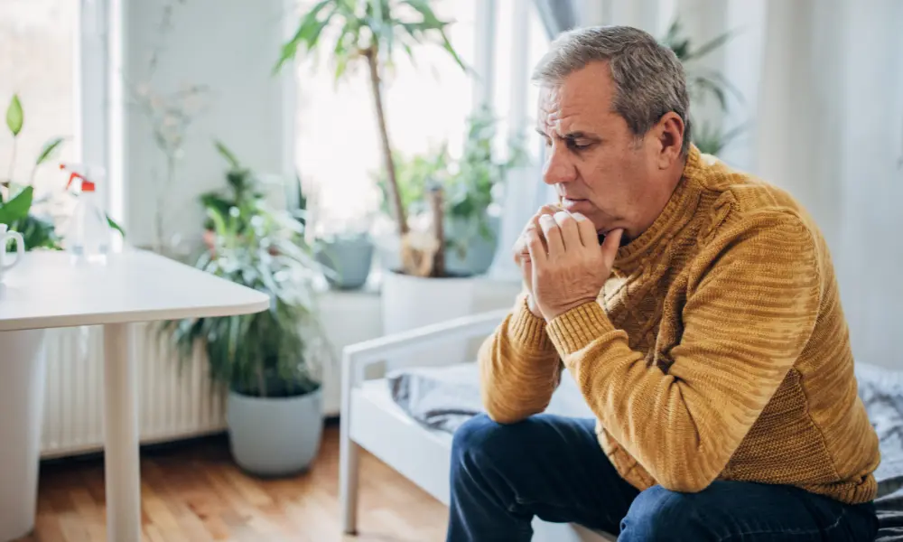 A man sits with a worried expression