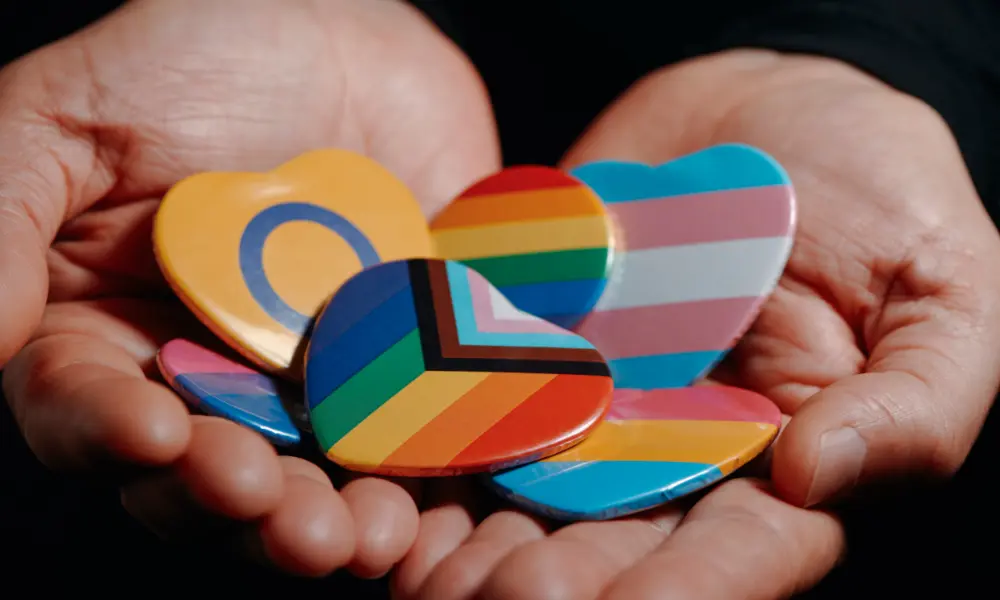 hand-holding-pride-flag-pins a pair of hands hold numerous pride pins