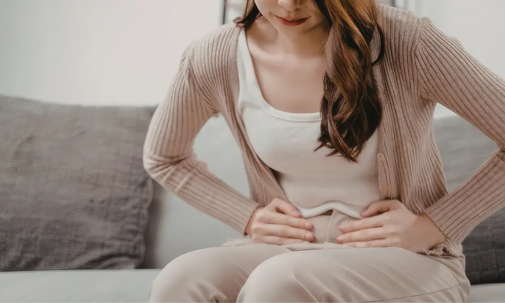 pelvic-pain (1) Someone holding their pelvis in discomfort while sitting