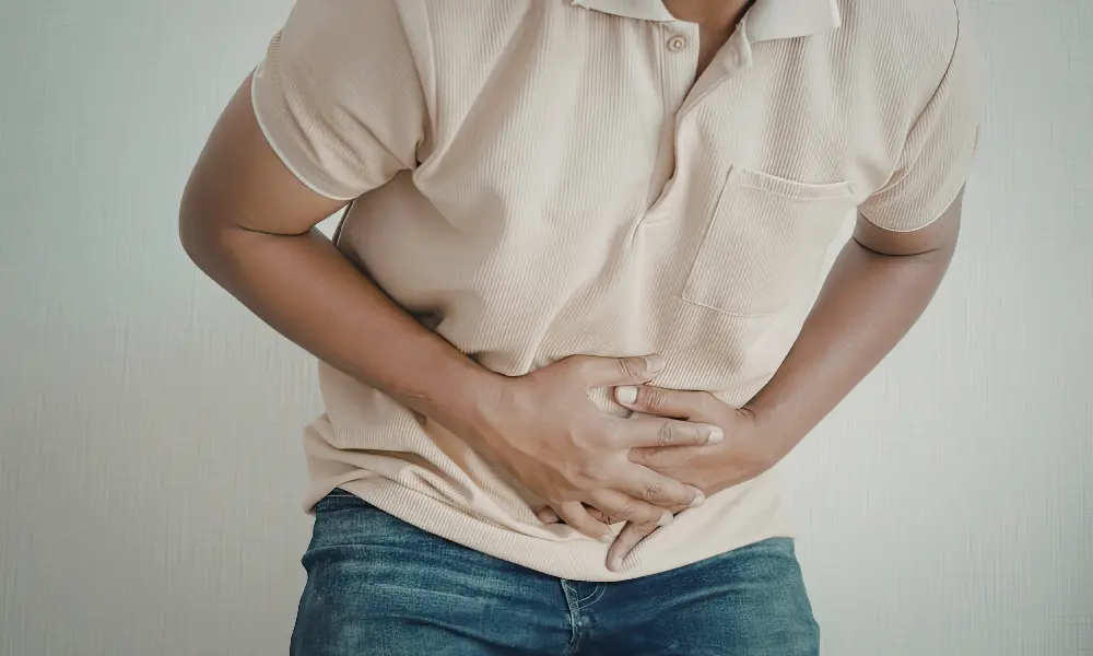 pelvic-pain a man leans while holding his abdominals in pain
