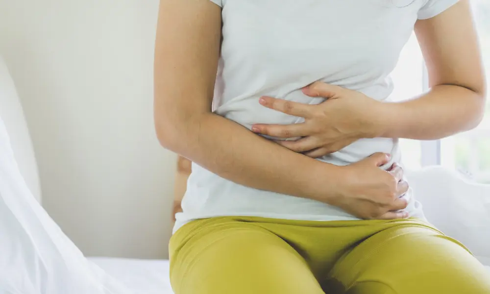 A close up of someone holding their stomach area in discomfort
