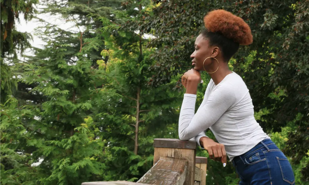 Woman ponders while leaning against a fence